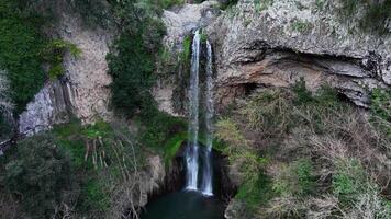 Majestic Waterfall Cascading Down Rugged Cliffs Surrounded by Lush Greenery in a Serene Natural Setting video
