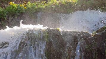 waterfall on a sunny day and drops of water flying around illuminated by the backlight of the sun. Nature of the highlands of the Ukrainian Carpathians video