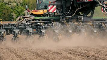 Close-up of seed drill in action in the field, A close-up shot of a seed drill operating in a field, with dust rising as it plants seeds into the soil. video