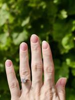 Japanese hygienic manicure on the female hand of the bride with a wedding ring. Clean and safe manicure. Beautiful fingers and nails without gel polish. Vertical photo