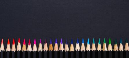 Creative minimal banner. Colored pencil set arranged in line on black background photo