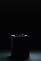 A black background with the silhouette of a gift box slightly off-center, ideal for promotional banners with copy space photo