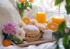 Breakfast in bed with a tray of pancakes, orange juice, and fresh flowers, with a relaxed atmosphere photo