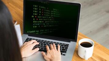 A woman typing on a laptop with code on the screen photo