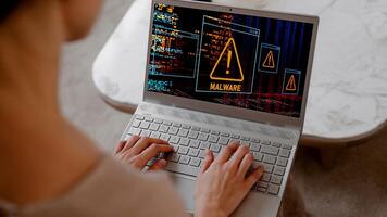 A man using laptop in his home and getting warning alerts on screen, Cyber attack on computer network photo