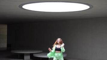 A dancer in neon outfit performs dynamic moves under skylight with captivating choreography video