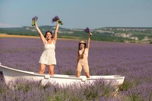women and girl standing in a field of lavender, holding flowers and smiling. They are in a small boat, which is floating on lavender photo