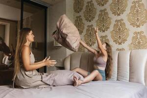 mom and daughter playing with pillows on a bed photo