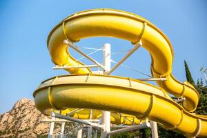 Water Slide, Amusement Park, Summer Fun - A yellow water slide curves through the air, offering a thrilling ride for visitors at an amusement park. photo