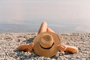 A woman is laying on the beach wearing a straw hat. She is relaxed and enjoying the sun. photo