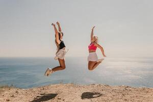 Two women are jumping in the air on a beach photo