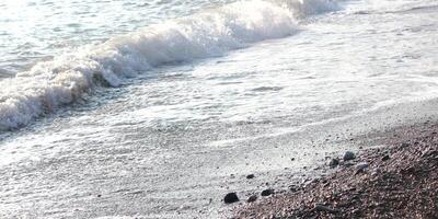 Sea surf. Photo of water at sunset. Small waves on a stony pebble beach.
