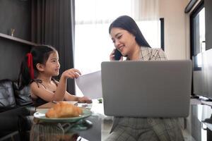 Working Mother and Daughter Collaborating at Home. Remote Work and Family Interaction photo