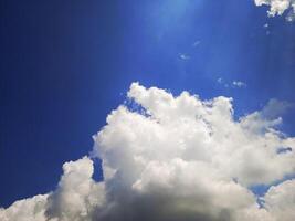 A blue sky with clouds and a plane flying in it photo