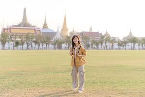 A Traveler Asian woman in her 30s exploring Wat Pra Kaew. From stunning architecture to friendly locals, she cherishes every moment, capturing it all in her heart and camera for years to come. photo
