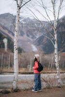 Scenic journey, Asian woman in a pink fleece explores Japan. Alone by the lake, an elegant portrait capturing the excitement and achievement of an adventurous trip. photo