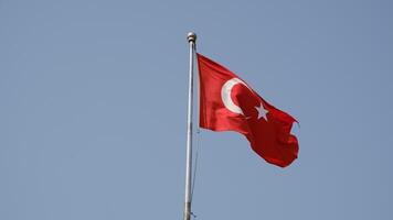 Turkish national flag on blue sky background. The flag on a flagpole flutters in the wind. The white star and crescent moon on red background. video