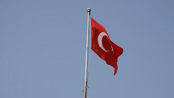 Turkish national flag on blue sky background. The flag on a flagpole flutters in the wind. The white star and crescent moon on red background. video