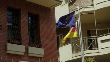 Flags of Germany and the European Union are displayed in front of the German Embassy in Tbilisi, Georgia, against the backdrop of private residences. Slow motion video