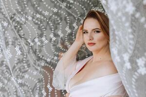 A woman is posing in front of a curtain with a lace veil on her head photo