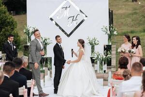 A bride and groom are getting married in front of a large crowd photo