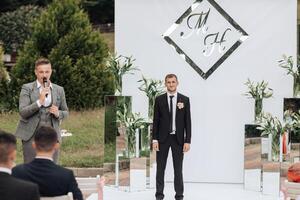 A man stands in front of a white wall with the letters M and H on it photo