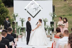 A bride and groom are getting married in front of a large crowd photo