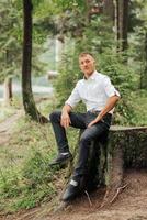 A man is sitting on a log in a forest photo