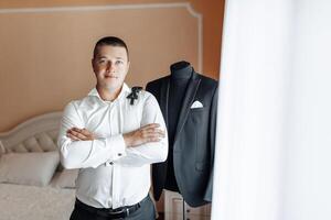 A man in a suit stands in front of a mannequin wearing a black suit photo