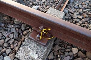 Close-up of a rusty railway track with a yellow ribbon tied around a bolt. photo