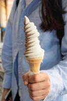 Hand holding a soft serve ice cream cone with vanilla and chocolate twist. photo