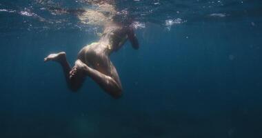 Freediver woman swims and relax in transparent fresh water lake, underwater view video
