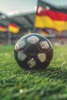 closeup of a soccer ball on grass in a stadium with blurred fans and flags of Germany in the background photo