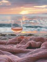 A glass of rose wine on pink blanket at sea beach with sunshine in background photo