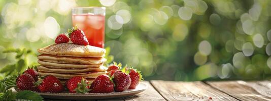 A stack of fluffy pancakes topped with fresh strawberries with a glass of red strawberry drink on a wooden table with blurred green bokeh background photo