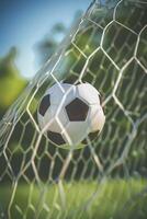 A soccer ball in goal post net with green field background photo