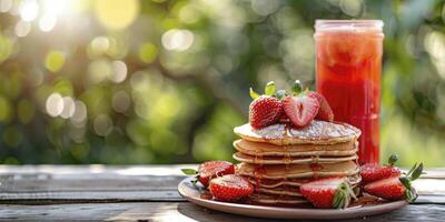 A stack of fluffy pancakes topped with fresh strawberries with a glass of red strawberry drink on a wooden table with blurred green bokeh background photo