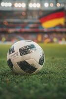 closeup of a soccer ball on grass in a stadium with blurred fans and flags of Germany in the background photo