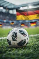 closeup of a soccer ball on grass in a stadium with blurred fans and flags of Germany in the background photo