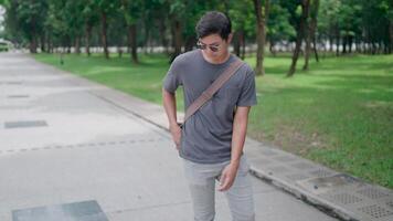 Businessman talking on the phone and rushing to get to work on time while working remotely, Man walking with laptop and bag in the park, working online, studying online, modern tech concept. video