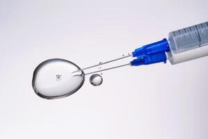 A drop of medicine flowing from a syringe with a needle. photo