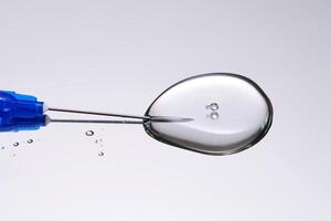 A drop of medicine flowing from a syringe with a needle. photo