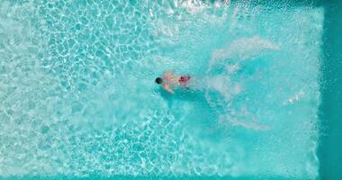 Aerial view as a man dives into the pool and swims. Slow motion video