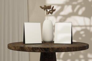 Two blank calendar sitting on a table in front of a vase of dried reeds photo