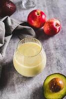 Organic mixed drink of avocado, apple and yogurt in glass on table vertical view photo