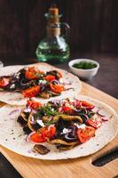 Delicious tacos with fried mushrooms, tomatoes, onions and feta on a board vertical view photo