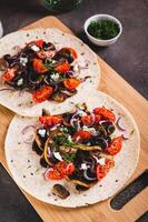 Tortilla with mushrooms, tomatoes, ricotta and onions on a board vertical view photo