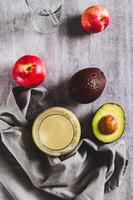 Organic mixed drink of avocado, apple and yogurt in glass on table top and vertical view photo