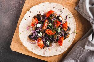 Close up of tacos with fried mushrooms, tomatoes, onions and feta on a board top view photo