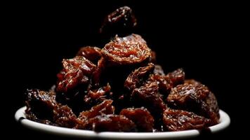 Raisins or dried grape in a bowl rotating on black background video